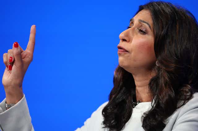 Suella Braverman holding up an index finger as she delivers a speech.