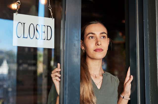 Woman standing next to a shop sign that says closed