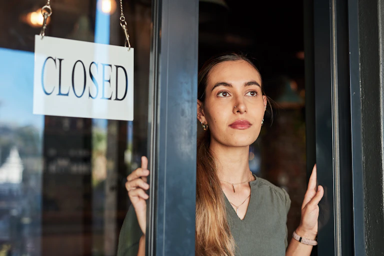Woman standing next to a shop sign that says closed