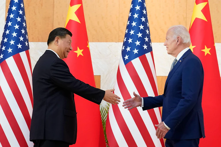 President Xi and president Xi meet at the G20 summit, shake hands in front of their flags.
