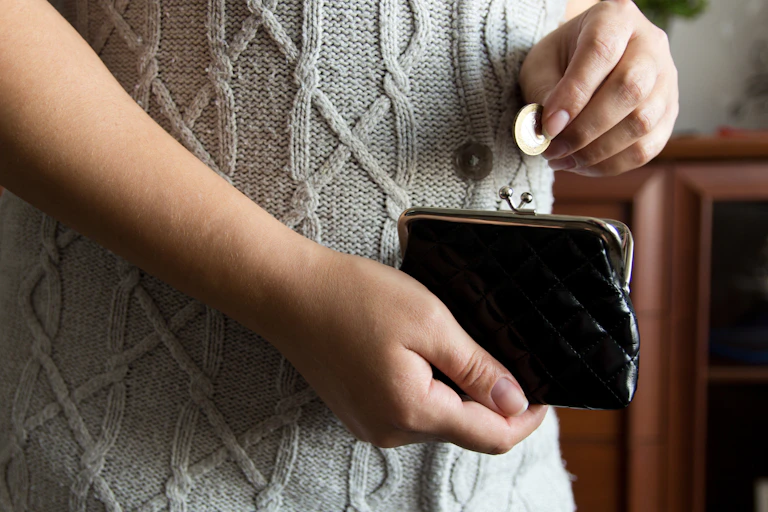 Photo of a woman's hands pulling a single pound coin out of a small purse
