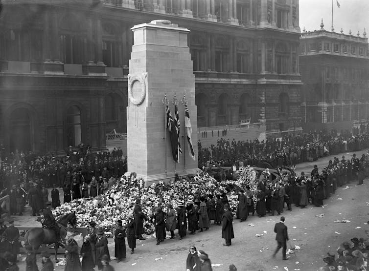 An archival photograph of people queueing to visit a war memorial in 1920.