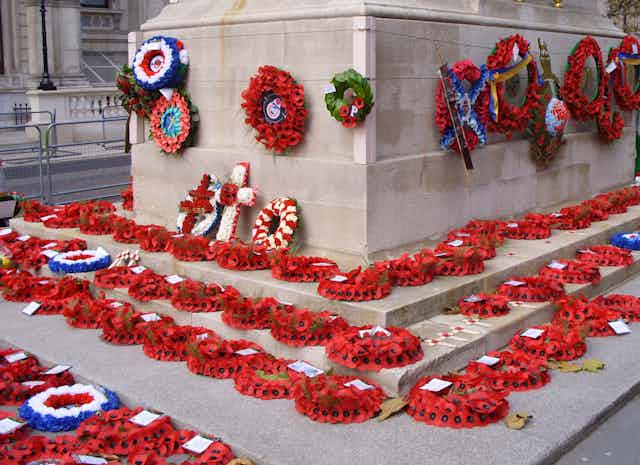 Wreaths of poppies placed on the steps and affixed to the sides of a war memorial.