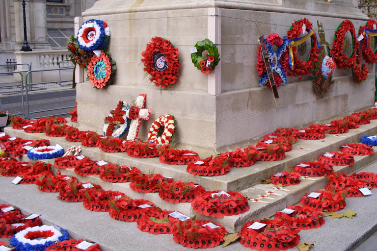 Wreaths of poppies placed on the steps and affixed to the sides of a war memorial.
