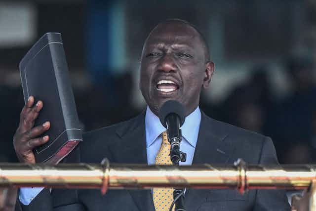 Kenya President William Ruto takes the oath of office with a Bible in one hand.