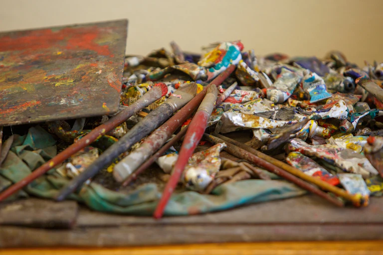 Pinceles y trapos llenos de pintura sobre una mesa.