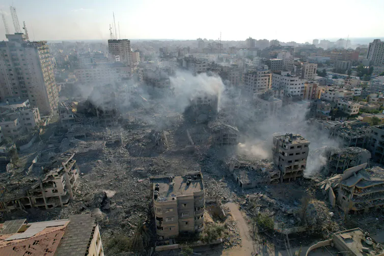 Asap mengepul dari gedung-gedung yang hancur di Kota Gaza setelah pengeboman Israel.