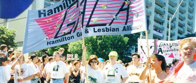 People under banner for Hamilton Gay and Lesbian Alliance at Pride Parade, 1991