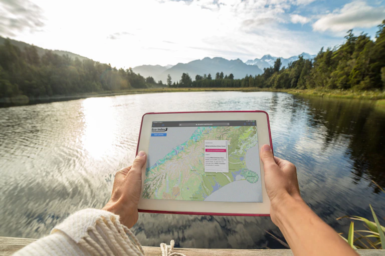 Someone at a lake or river, holding a digital device with the Eco index restoration map showing.