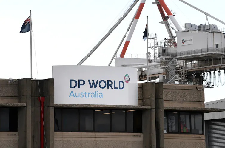 A sign on a concrete building that reads DP World Australia with a crane in the background