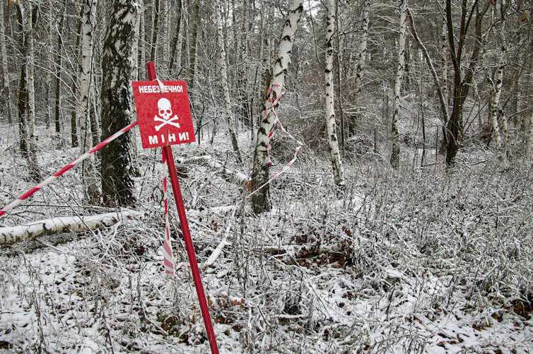 sign in Ukrainian warning of landmines, snowy forest