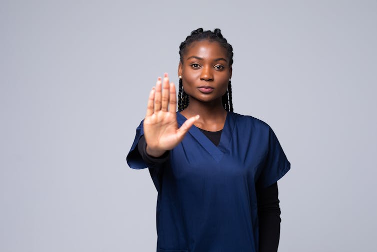 nurse stands with hand in front of her to say stop