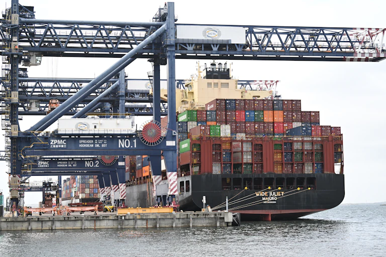 Large container ship being unloaded by cranes at a dock