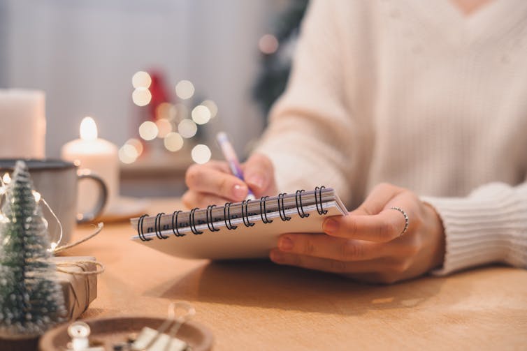 person with notepad, small christmas tree on desk