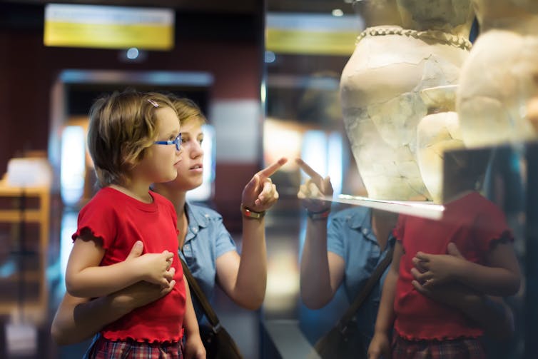 A girl and her mum look at ancient pottery.