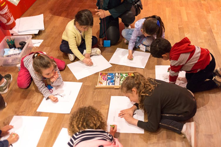 Children on the floor drawing.