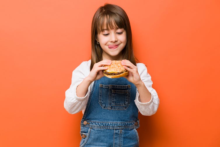 girl looks hungrily at hamburger