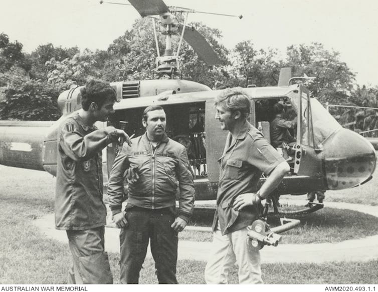 Two journalists and a US pilot stand by a heicopter in Cambodia, 1971.
