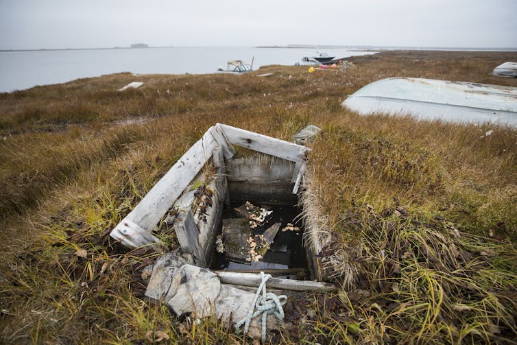 A wooden box in the soil filled with water in Arctic landscape.