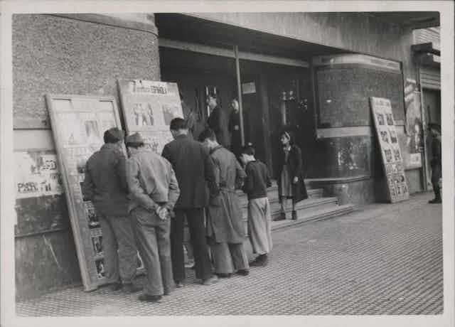 Ciudadanos ante la cartelera del cine Avenida de Burgos en 1938, tras la conquista de la ciudad por el bando franquista.