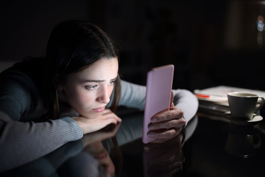 A young girl looks at her smartphone with concern.