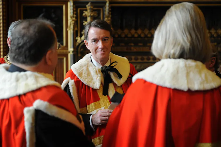 Peter Mandelson and two other peers talk while wearing their traditional scarlet and ermine robes.