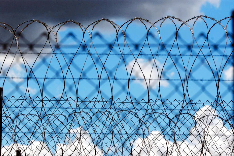 Prison wire is set against some clouds.