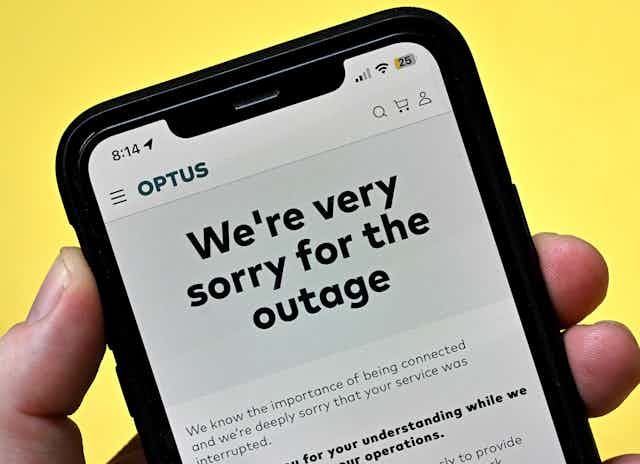 A phone screen on yellow background stating "we're very sorry for the outage"
