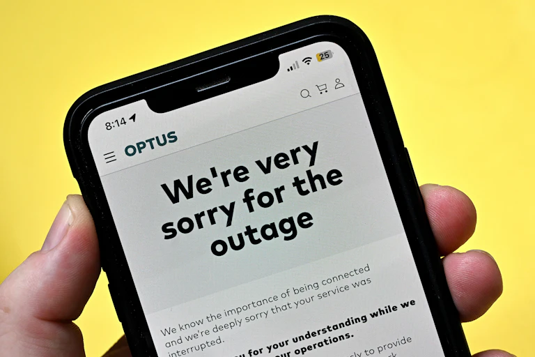 A phone screen on yellow background stating "we're very sorry for the outage"