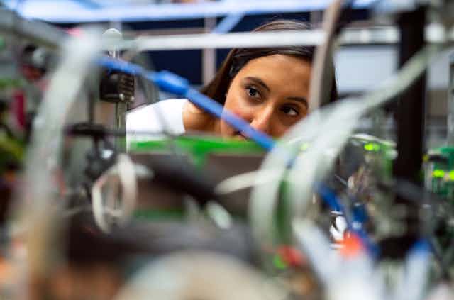 A woman looks at wires in a lab.