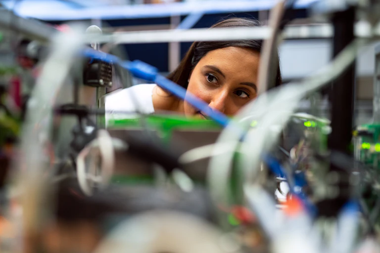 A woman looks at wires in a lab.