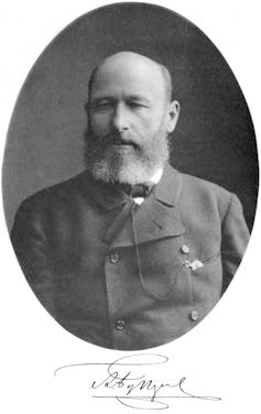 An old black and white photograph of a bald, bearded man wearing an old-fashioned coat.