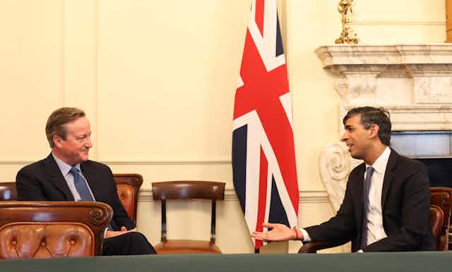 David Cameron and Rishi Sunak talking in front of a union flag
