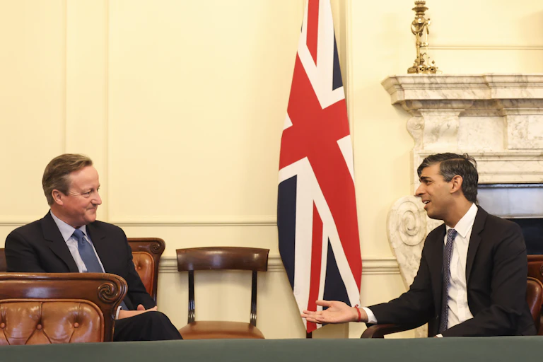 David Cameron and Rishi Sunak talking in front of a union flag