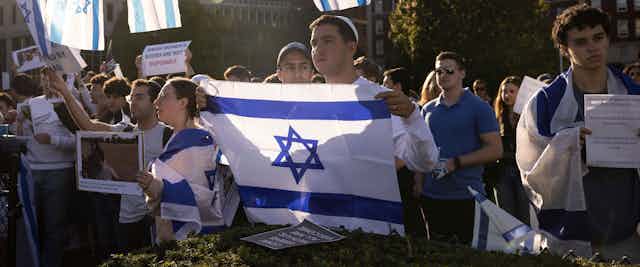 People seen holding Israeli flags with sombre faces.