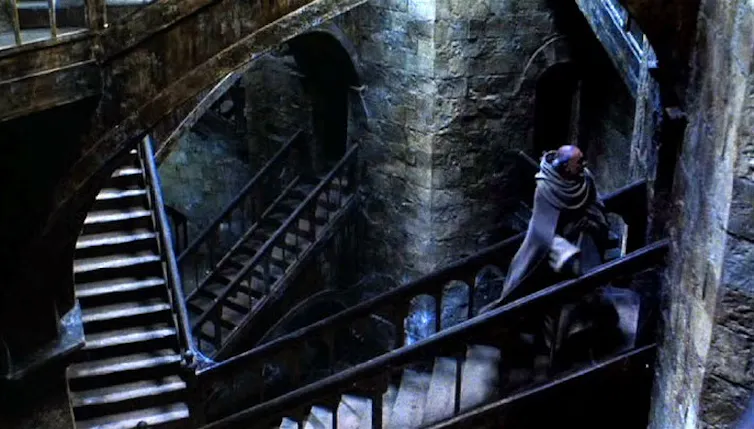 Interior de un edificio de piedra con escaleras laberínticas.
