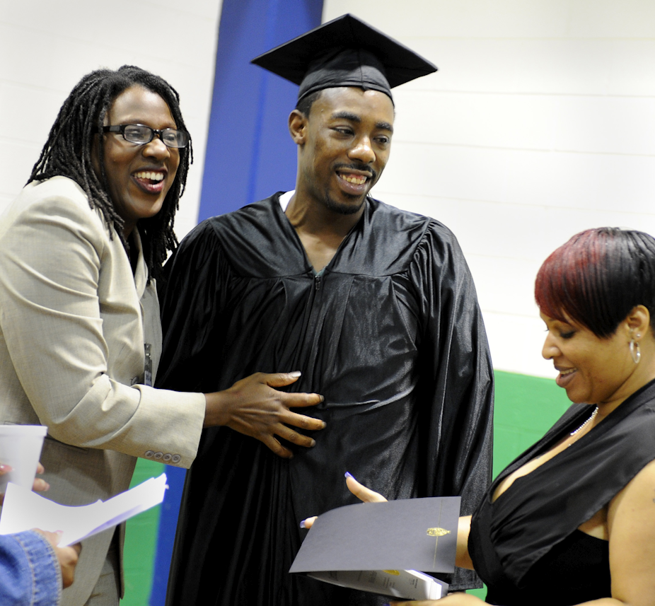 A man in a graduation cap and gown receives a diploma.