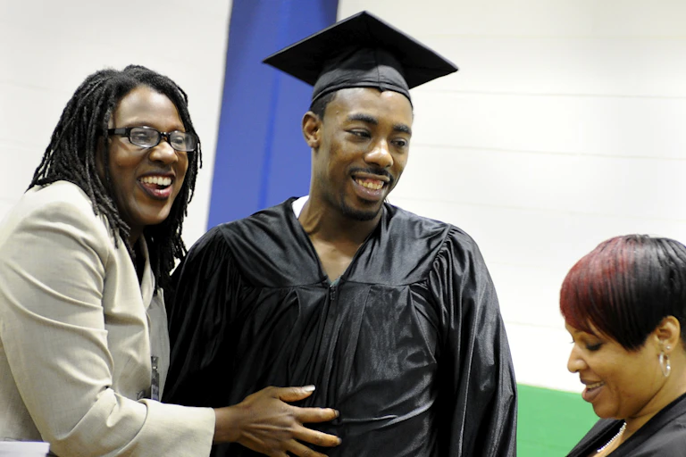 A man in a graduation cap and gown receives a diploma.