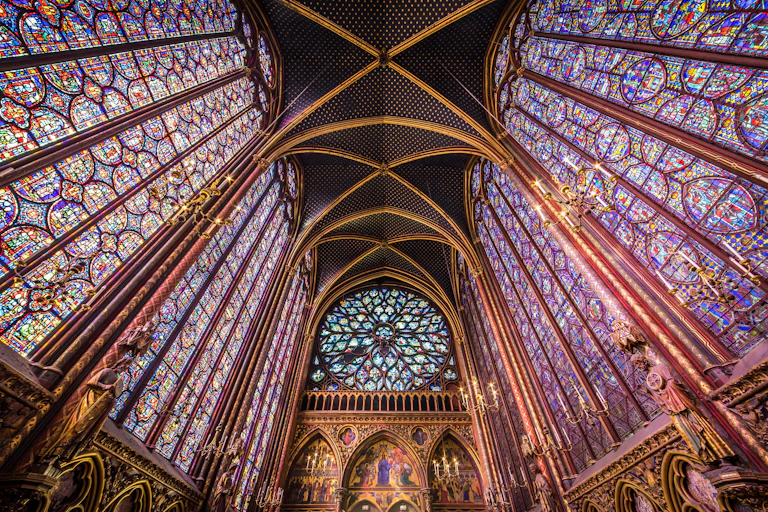 Fotografía de un techo pintado de azul lapislázuli y unas vidrieras que cubren todas las paredes, coronadas por un rosetón.