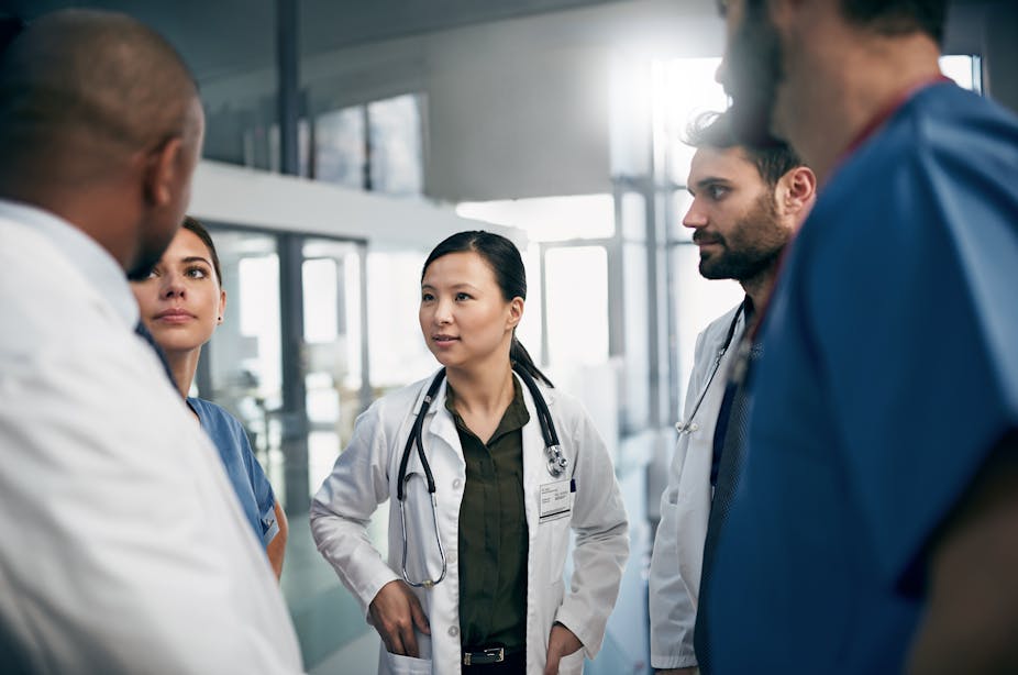 A diverse group of doctors have a discussion in a hospital setting.