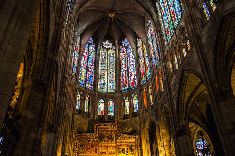 The interior of a cathedral, with stained glass windows illuminating the nave.