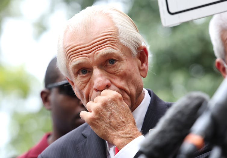 A man in a suit with white hair looking pensive.