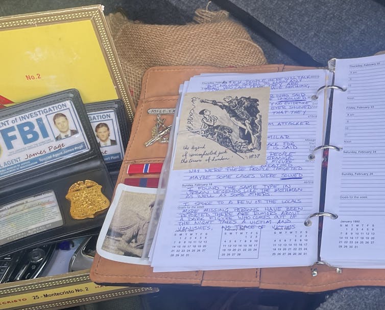Open notebook with handwritten notes in it next to two FBI badges.