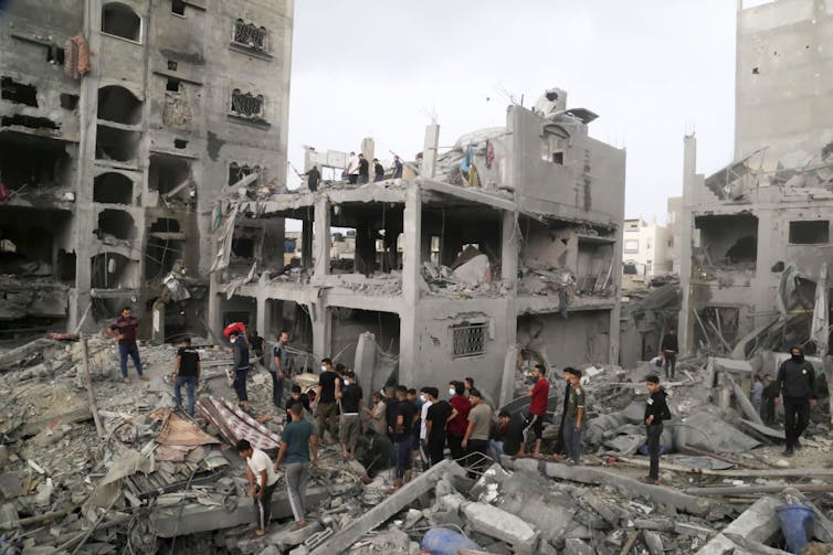 Men walk through a bombed refugee camp in Gaza looking for survivors.