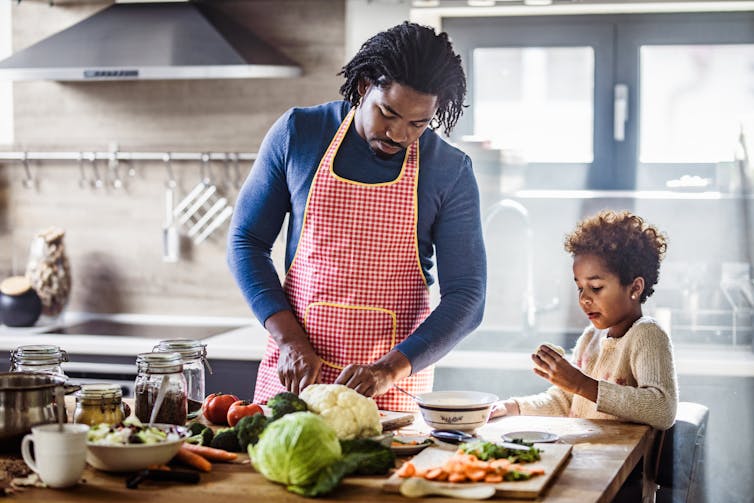 A man preparing food in the kitchen with his daughter.