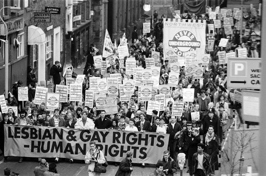 Black and white photo of protest march with placards and banner reading "Lesbian and gay rights - human rights"