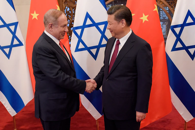 Israeli president Benjamin Netanyahu shakes hands wioth Chinese president Xi Jinping with the two ocuntries' flags in the background.