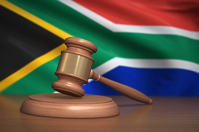 A judge's gavel in front of the South African flag.
