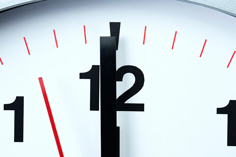 A clock with hands just before midnight.