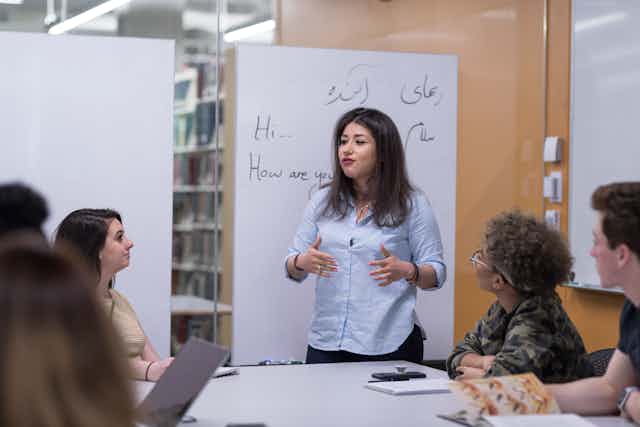 Woman stands in front of small group of seated students